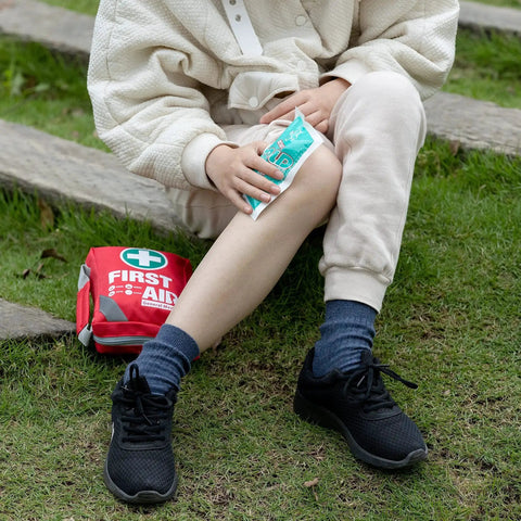 Person using instant cold pack from Compact 175 Piece First Aid Kit with Reflective Bag Design in outdoor setting