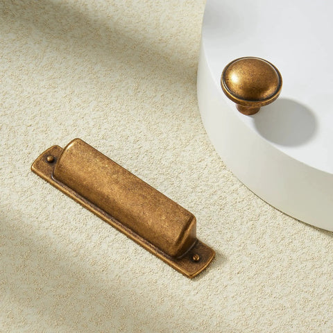 10 Pack Antique Brass Cup Pulls For Kitchen Cabinets And Furniture, 3 Inch Hole Center Drawer Pulls with a matching knob on white surface