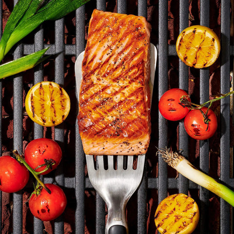 Grilling Tool Precision Turner For Effortless Burger Flips And Flaky Fish Fillets With Thin Beveled Head Non Slip Grip And Hanging Ring OXO Good Grips Black, lifting grilled salmon on a barbecue.