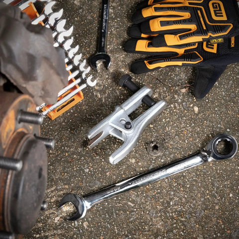 Adjustable Ball Joint Separator for Front Wheel Drive Cars and Light Trucks next to wrenches on garage floor