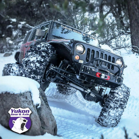 Off-road vehicle climbing snowy terrain with Yukon Gear & Axle branding on windshield