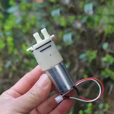 Compact DC 6V 9V 12V Micro 370 Motor Self Priming Diaphragm Water Pump held in hand, showing connectors and wiring.