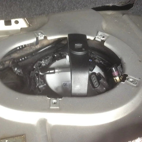Universal Gas Tank Lock Ring Tool in use for fuel pump sender removal in vehicle trunk, showing close-up of tool applied.