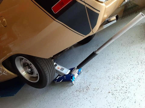 Car lifted by ✝️ 3000 Lb Aluminum Racing Car Auto Floor Jack Low Profile Rapid Pump Lift for wheel replacement and repairs.
