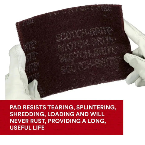 Gloved hands holding General Purpose Very Fine Grade Hand Pad 6 by 9 Aluminum Oxide Pack of 20 Maroon