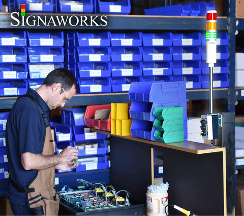 Man working in a warehouse next to Ultra Bright 4 Stack LED Andon Tower Light With 3 Position On Off Flash Switches Red Amber Green Blue LEDs 8 Ft Industrial Power Cord No Brainer Plug And Play Ready Indoor OSHA Rated Made In USA