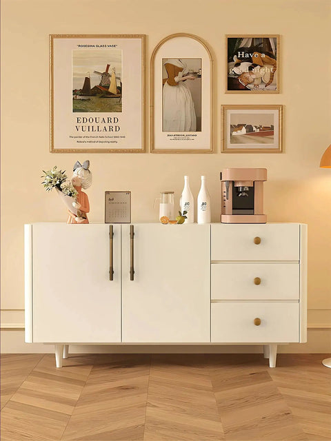White sideboard with drawers featuring antique brass cabinet knobs, wall art above, modern wooden floor, home decor setting.