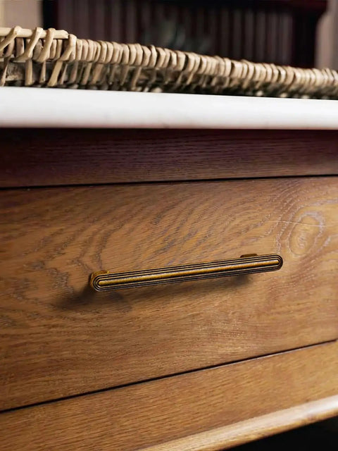 Close-up of installed 3-inch antique brass cabinet pull on a wooden drawer, part of the 10 Pack Antique Brass Cabinet Pulls 3 Inch 76mm.