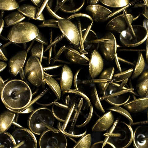 Close-up of antique brass upholstery tacks, 100 pcs per box, with 7/16 inch head and 1/2 inch shank for securing fabric and trim.