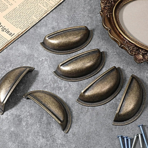 Brass Bronze Cup Drawer Pulls Set Twelve Pack Cabinet Cup Pulls arranged on a table with screws, 3 inch spacing.