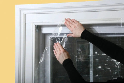 Applying the Indoor Shrink Window Kit for Large Windows and Patio Doors, 84 Inch By 110 Inch Clear Film on a window frame.