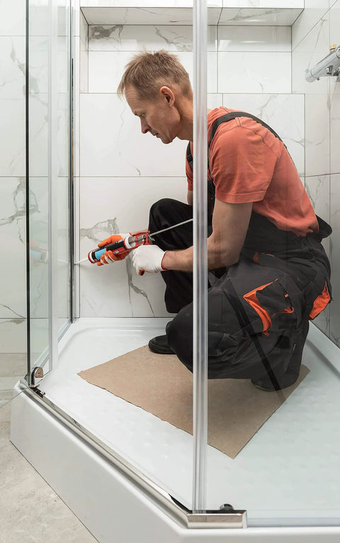 Man using Black 100 Percent Silicone Sealant Caulk For General Purpose Use Waterproof Odor Free No Yellowing Color Stable Ten Point One Ounce Cartridge Quick Cure In About 30 Minutes Ready For Water Exposure in a shower