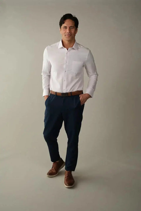 Man wearing Athletic Fit White Dress Shirt For Men With 4 Way Stretch Performance, Wrinkle Free And Stain Resistant, standing confidently.