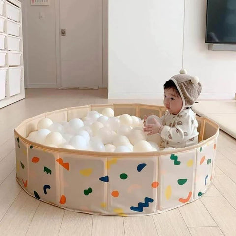 Baby playing in beige ball pit with 100 Ball Pit Balls Phthalate Free BPA Free Crush Proof Plastic in colorful playroom setting.
