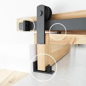 Close-up of 8.2 FT Heavy Duty Sturdy Sliding Barn Door Hardware Kit, Black, showing door rollers and floor guide on wooden panel