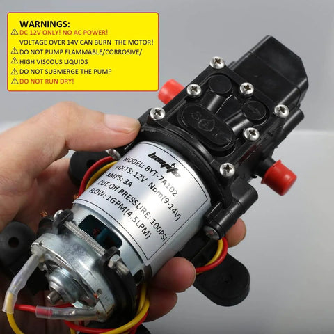 Close-up of bayite 12V DC Fresh Water Pressure Diaphragm Pump with label and wiring, held in hand, showing specifications and warnings.