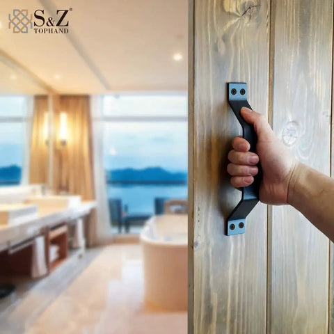 9 Inch Sliding Barn Door Handle Set In Black For Interior And Exterior Doors, Heavy Duty Pull Handle For Sliding Barn Doors, Easy To Install, Rust Resistant Carbon Steel With Frosted Black Finish being held by a hand on a wooden door in a luxurious bathroom background.
