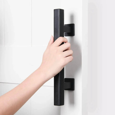 Hand holding Heavy Duty 12" Pull and Flush Barn Door Handle Set, Large Rustic Two-Side Design, Solid Steel Square Black on white door