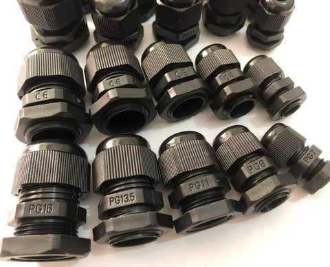 Various sizes of black PG cable glands arranged on a white surface