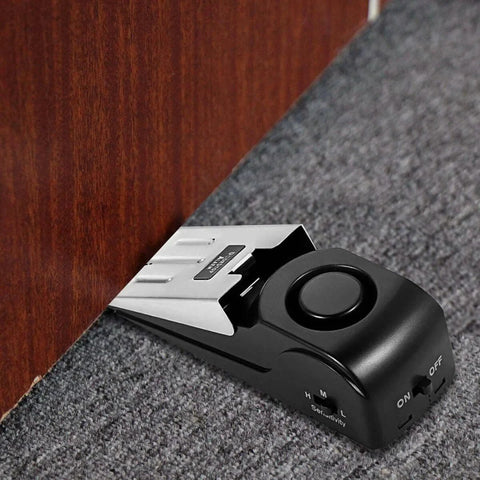 Black Door Stop Alarm with 120DB Siren for Home & Travel installed under wooden door on carpet