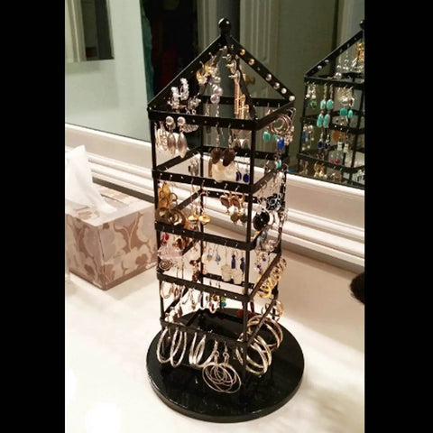Black jewelry holder with multiple earrings displayed, made from metal, situated on a countertop