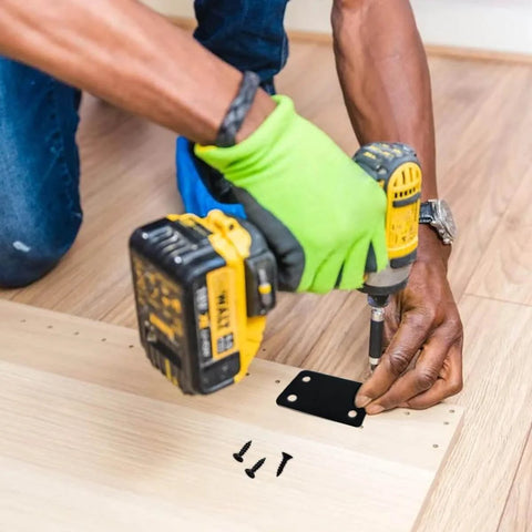 Installation of a black metal flat straight brace bracket, 2.4 x 1.5 inch, on wooden surface using a drill and screws.