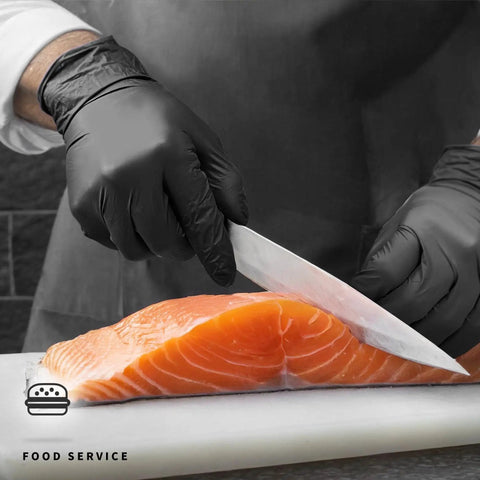 Person wearing Black Nitrile Disposable Gloves 4.5 Mil Powder Free Latex Free Food Safe Exam while slicing salmon