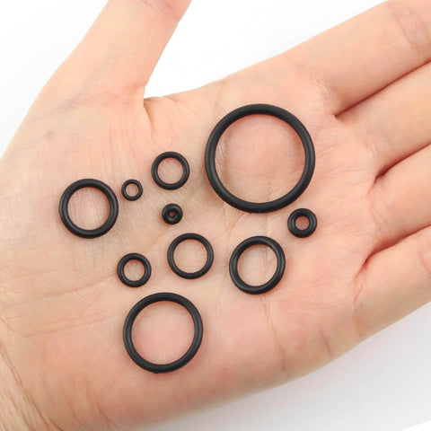 Different sizes of black rubber O rings from the 705 Piece O Ring Kit With 28 Metric Sizes, Premium Nitrile Black Rubber O Rings, Oil And High Temperature Resistant, Great For Automotive Repairs, Pipe Connections, Tap Sealing, And Air Or Gas Sealed Connections shown on a hand.
