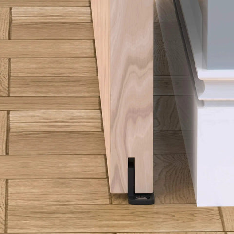 Sliding Barn Door Floor Guides Black 4 Pack Bottom Track Guides For All Sliding Doors Including Bypass And Pocket Doors Easy To Install Closet And Barn Style Durable Plastic Guides For Grooved And Non Grooved Tracks installed on wood floor with door.