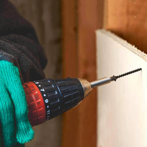 Hand using drill with #8 x 3/4 Inch Black Phosphate Stainless Steel Wood Screws into drywall