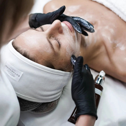 Esthetician using Black Vinyl Disposable Exam Gloves 4 Mil Latex Free Powder Free Medical 1000 during facial treatment