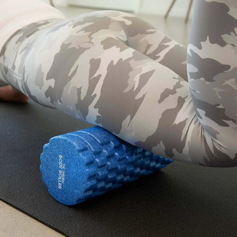 Person using High Density Foam Roller Massager with 3D Textured Rollers for leg muscle massage on yoga mat