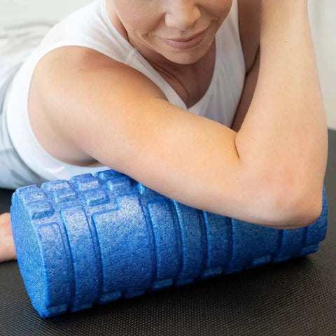 Person using High Density Foam Roller Massager with 3D textured rollers for deep tissue back and leg muscle massage on yoga mat.