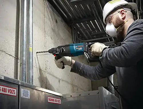Worker using Bosch Bulldog Extreme 1 Inch SDS Plus Rotary Hammer with 8 Amp motor for drilling in concrete pipe on job site