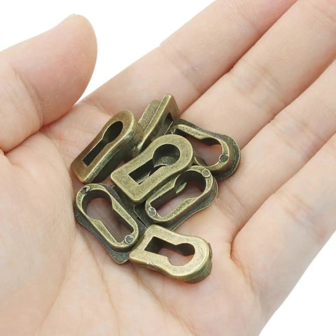 Hand holding 8Pcs Bronze Skeleton Key Covers For Furniture Keyholes Zinc Alloy Antique Style Keyhole Lids.