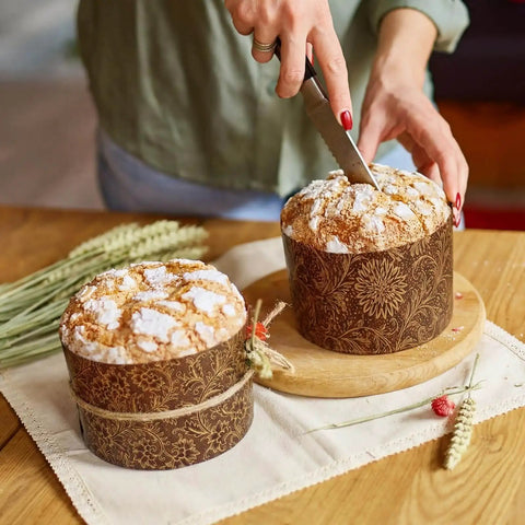 Person slicing Easter bread in 48 Pack Easter Panettone Paper Molds 15 Oz Nonstick Brown Round Paska Kulich Baking Molds Pans