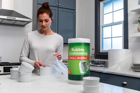 Woman using Bubble Wrap Protective Packaging 12 Inch Wide 30 Foot Roll Clear Bubble Cushions For Delicate Items Reusable Recyclable on dishes.