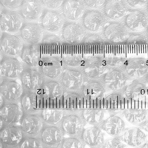 Close-up of Bubble Cushioning Wrap For Fragile Items Perforated 12 Inch Roll 175 Ft Clear With Small Three Sixteenth Inch Bubbles with ruler