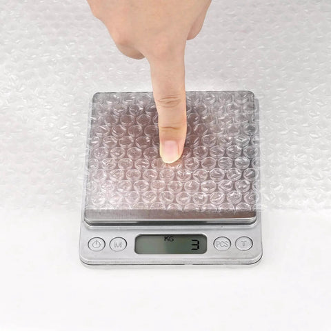 Finger pressing down on 2 Pack 12 Inch Bubble Packing Wrap 72 Feet Perforated Every 12 Inches for Moving Boxes and Shipping Cushioning