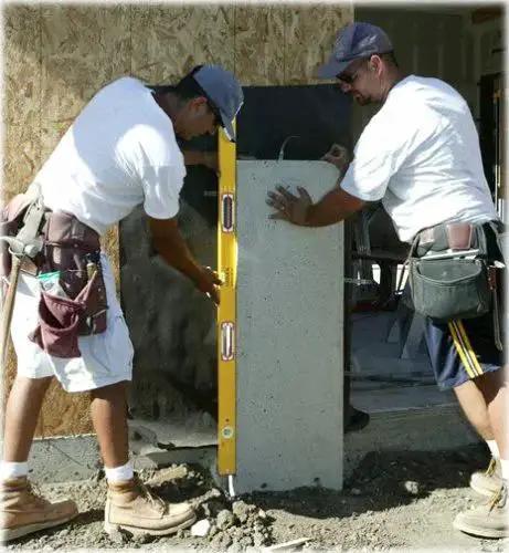 Two builders using Stabila 37448 48-Inch Builder's Level with reinforced frame and three vials on a concrete wall for accuracy