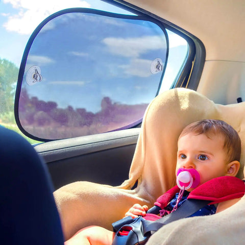 Baby with pacifier sitting in car, protected by transparent PVC sunshade on window