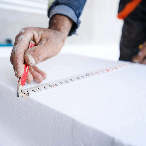 Person using 25-foot steel retractable tape measure with fractions for precise measurement on white surface.