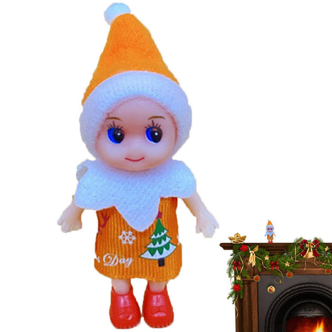 Toy doll in orange outfit with white trim and hat, standing on a mantel decorated for Christmas with a small tree design.
