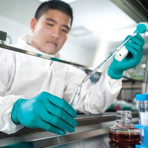 Scientist wearing A7 Cleanroom Lab Coat with High Collar and Thumb Loops, performing lab work in anti-static, low lint apparel.