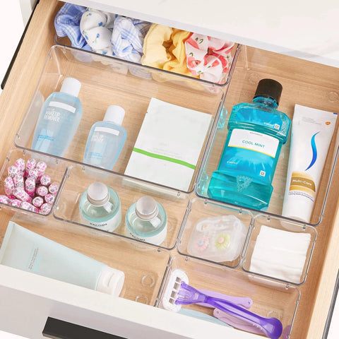 Clear Plastic Drawer Organizer Set 25 Pieces in Four Sizes for Makeup Vanity Bathroom Kitchen and Office Declutter Drawer Space with Non Slip Pads arranged in a bathroom drawer.