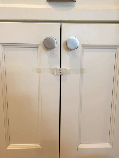 Installed self adhesive safety latch on cabinet doors, clear multi use straps for cabinets, fridges and freezers with four flaps.
