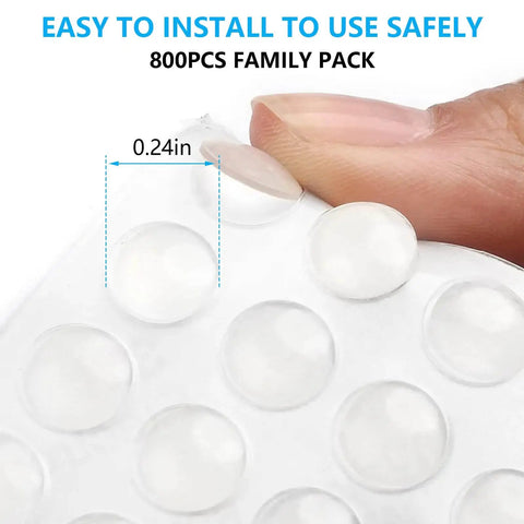 Close-up of 800 Pack Clear Cabinet Door Bumpers Self Adhesive Cushions for Cabinets, Drawers, Frames and Furniture No Hassle Quiet Close Invisible 0.24 Inch Silicone Stoppers for Noise Reduction and Surface Protection on fingertip, showing self-adhesive backing and 0.24 inch size.