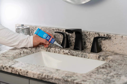 Person applying Clear Silicone Sealant All-Purpose Waterproof Adhesive 2.7 Fl Oz Tube for sinks on a bathroom countertop.