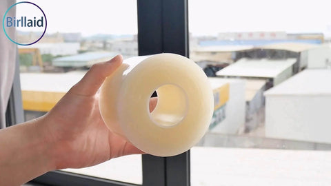 Hand holding Window Weather Sealing Tape, 3 Inch x 165 FT(55 Yards), clear roll near a window