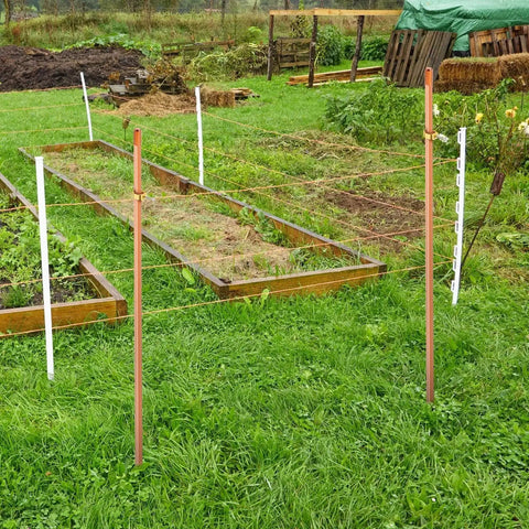 Grounding Rod Kit Zonon With Five Eighth Inch Copper Clad Grounding Rods And Clamps For Electric Fences installed in a garden.